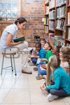 Cute pupils sitting on floor in library