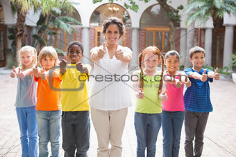 Pretty teacher standing with pupils in courtyard