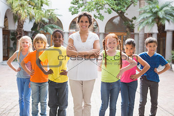 Pretty teacher standing with pupils in courtyard
