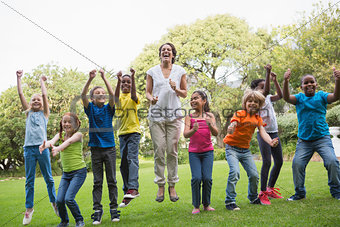 Pretty teacher jumping with pupils outside