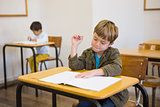 Pupil writing in notepad at his desk