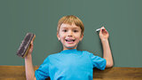 Happy pupil holding chalk and duster in classroom