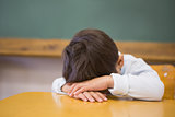 Sleepy pupil napping at desk in classroom