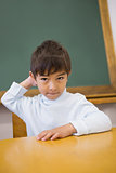 Cute pupil sitting at desk in classroom