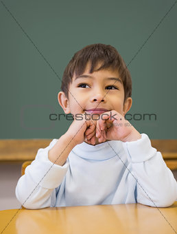 Cute pupil thinking at desk in classroom
