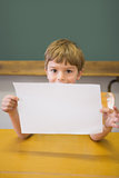 Cute pupil smiling at camera in classroom showing page