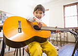 Cute pupil playing guitar in classroom
