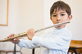 Cute pupil playing flute in classroom