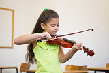 Cute pupil playing violin in classroom