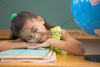 Cute pupil napping in classroom with globe