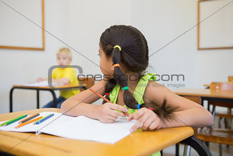 Cute pupils colouring at desks in classroom