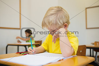 Cute pupils colouring at desks in classroom