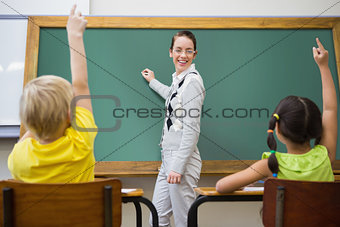 Pretty teacher writing on chalkboard
