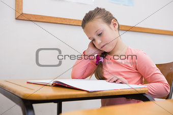 Cute pupil reading at her desk