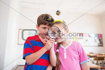 Cute pupils looking through magnifying glass