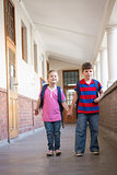 Cute pupils holding hands in corridor