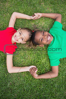 Cute children smiling at camera outside on the grass