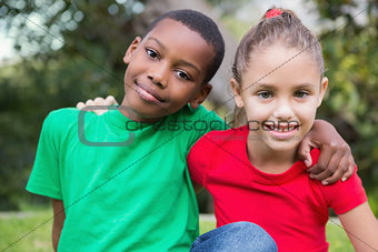 Cute children smiling at camera outside on the grass