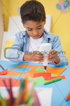 Cute little boy making art in classroom