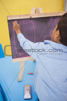 Cute little boy drawing on chalkboard