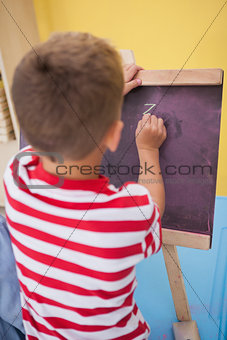 Cute little boy drawing on chalkboard