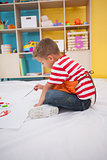 Cute little boy painting on floor in classroom
