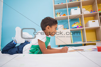 Cute little boy painting on floor in classroom