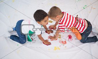 Cute little boys painting on floor in classroom