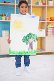 Cute little boy showing his painting in classroom