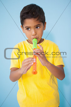 Cute little boy playing the recorder in classroom