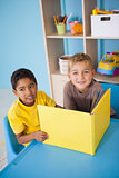 Cute little boys reading at desk in classroom