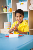 Cute little boy playing with modelling clay in classroom
