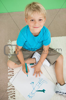 Cute little schoolboy smiling at camera while drawing