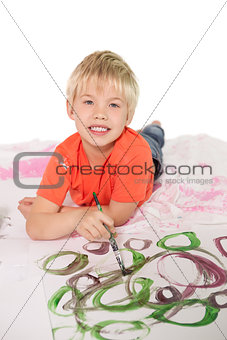 Happy little boy painting on the floor