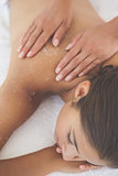 Beautiful brunette lying on massage table with salt scrub on back