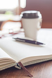 Open notebook with pen and coffee cup