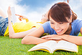 smiling pretty students lying on the grassland with books