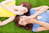 two asian sisters whispering gossip on the grass