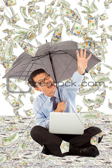 happy business man holding a umbrella and catching money