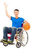 young man sitting on a wheelchair and holding a basketball