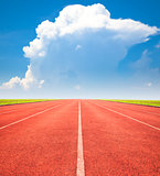 red running track over blue sky and clouds
