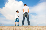father and son standing on a stone platform and pee together 