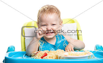 Little blond boy eating spaghetti and laughing