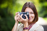 Young woman taking picture with retro camera outdoors