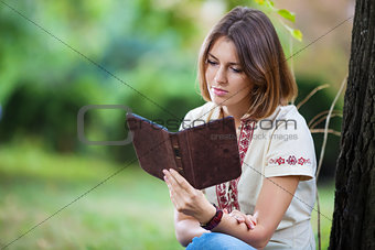 Young attractive woman reading e-book in summer park