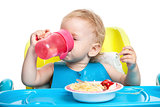 Little boy drinking water while sitting at table with plate of spaghetti