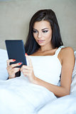 Beautiful young woman using a tablet in bed