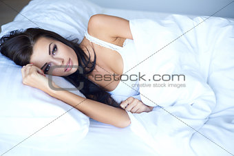 Young woman lying awake in bed thinking