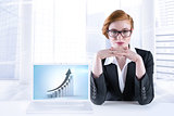 Composite image of redhead businesswoman sitting at desk