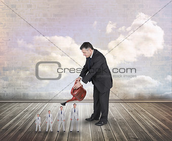 Composite image of mature businessman watering tiny businessman